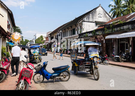 Strada tipica scena con tuk Tuks e negozi nel quartiere coloniale della città vecchia. Sisavangvong Road, Luang Prabang, Louangphabang provincia, Laos, Asia Foto Stock