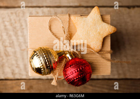 Natale fatti a mano scatola regalo decorata con artigianato e carta oro rosso palle e cookie fatti a mano star su vintage sfondo di legno vista dall'alto. Merry Cristo Foto Stock