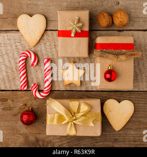 Composizione di natale di varie confezioni regalo avvolto in carta artigianale e decorato con raso rosso in oro nastri e dolcezza vacanze gingerbread cookie Foto Stock