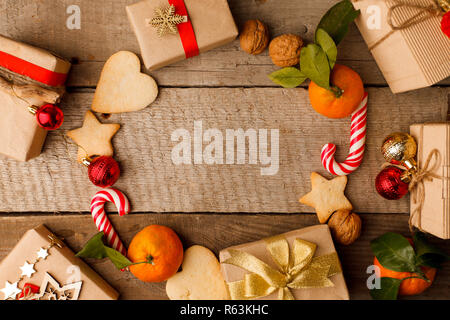 Composizione di natale di varie confezioni regalo in carta artigianale decorata oro rosso nastri e dolcezza vacanze gingerbread cookies, noce, candy cane. T Foto Stock