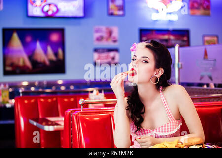 Ritratto di un giovane Pin'Up, volto in profilo, mettendo a patatine fritte nella sua bocca Foto Stock