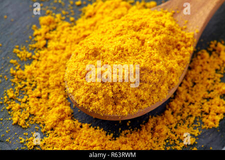 La curcuma in polvere (curcuma), noto anche come zafferano indiano, in cucchiaio di legno Foto Stock