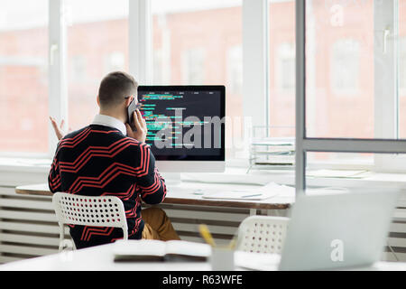 Specialista di codifica parla al telefono Foto Stock