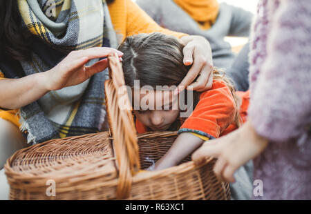 Una sezione mediana di una famiglia con due bambini piccoli aventi picnic in autunno la natura. Foto Stock