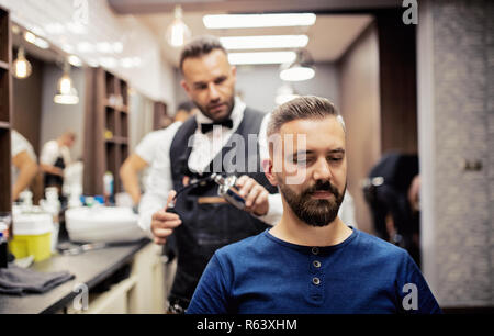 Hipster uomo client haidresser visita e un parrucchiere in un barbiere. Foto Stock