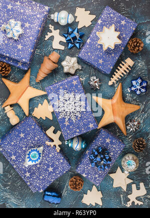 Creative composizione chritmas sfondo. Presenta in blu scuro la carta di avvolgimento con argento stelle brilla, decorazioni in legno, ornamenti, baubles Foto Stock