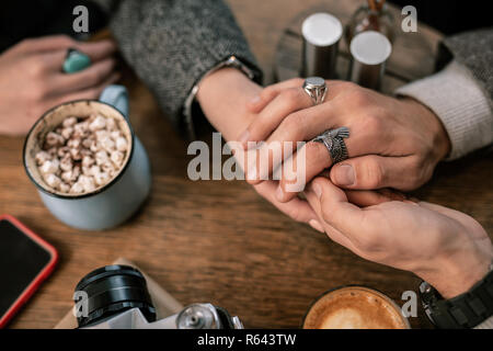 Romanticamente uomo donna tenendo le mani su un tavolo del bar Foto Stock