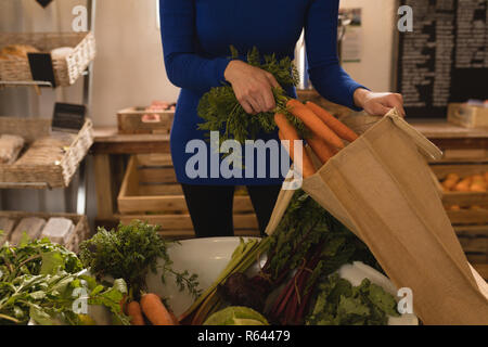 Donna mettendo vegetale in borsa per la spesa al supermercato Foto Stock