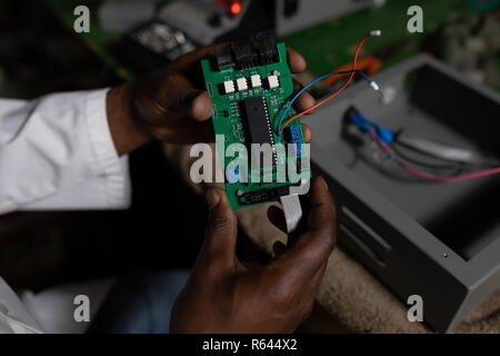 Lavoratore esaminando la scheda a circuito stampato in fabbrica del vetro Foto Stock
