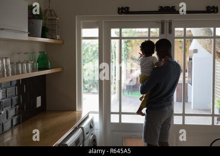 Padre e figlio guardando al di fuori della porta da cucina Foto Stock