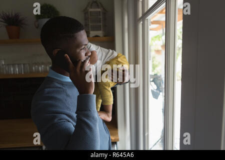 Padre con suo figlio nelle sue braccia parlando al telefono Foto Stock