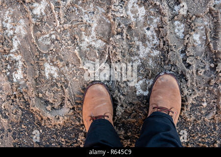 Mans piedi in scarpe invernali sulla neve sporca per le strade. Foto Stock