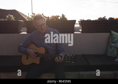 Senior uomo a suonare la chitarra in terrazza Foto Stock