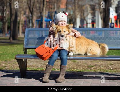 Bambino sorridente ragazza con cane seduto su un banco di lavoro Foto Stock