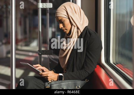 Donna con tavoletta digitale durante il viaggio in treno Foto Stock