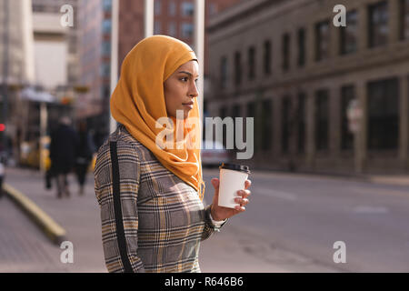 Donna con caffè in via della città Foto Stock