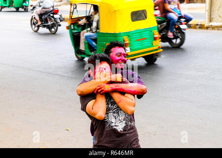 New Delhi, India - 10 marzo 2016: giovani indiani ragazzi con facce colorate celebrare Holi festival nelle strade e divertirsi con il rickshaw in background Foto Stock