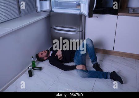 Uomo disteso sul pavimento in cucina Foto Stock