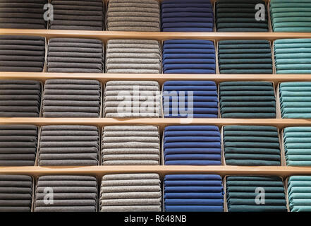 Vestiti visualizzato nel negozio. Spase di copia per il testo. Molto caldi maglioni di diverso colore sono impilate ordinatamente in fila sugli scaffali del negozio. Pile di variopinte a maglia indumenti di lana. T-shirt su accantonare Foto Stock