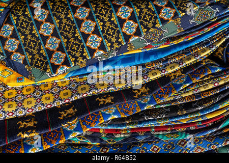 Lo sfondo da motley e multi-colore di tessuti di seta con un pattern. Foto Stock
