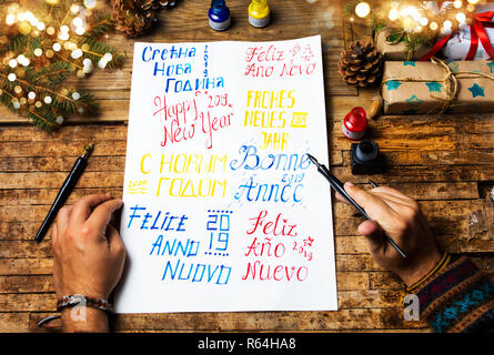 Persona scrivendo un felice anno nuovo carta in varie lingue Foto Stock