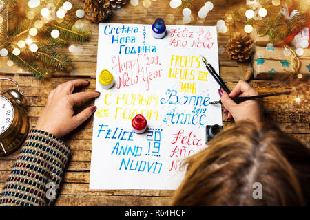 Persona scrivendo un felice anno nuovo carta in varie lingue Foto Stock