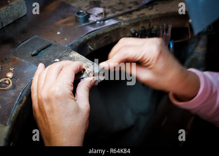 Gioielliere lavorando con un ago file un anello d'oro su un vecchio banco in autentici gioielli workshop Foto Stock