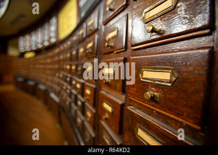 I cassetti in legno con ornamenti di metallo in una vecchia libreria. Scatole di legno con le schede indice nella libreria. Foto Stock