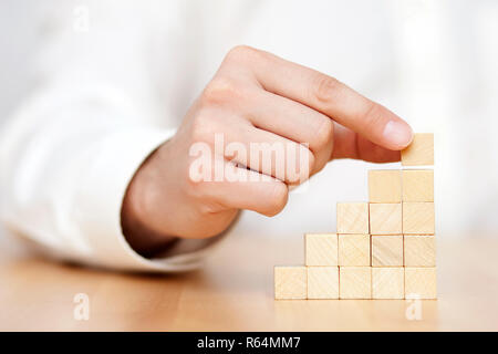 Mano d'uomo mettere dei blocchi di legno a forma di scala. Il successo aziendale concetto. Foto Stock