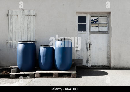 Tre blu barili di plastica su un pallet di legno all'esterno. Foto Stock