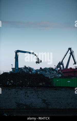 Una gru con pinze in azione sul cantiere di riciclaggio. Foto Stock