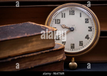 Panta Rhei concetto: antico orologio da tasca e la pila di vintage hard cover libri sulla pietra naturale dello sfondo. Foto Stock