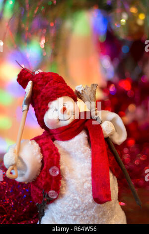 Pupazzo di neve di festa in rosso vestiti con una scopa e una pala sotto l albero di Natale su uno sfondo luminoso Foto Stock