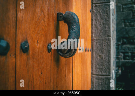 Un vecchio respingente metallico conformato a mano su una porta di legno di un borgo medievale Foto Stock