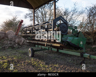 Mietitrebbia Barra falciante memorizzati in aperto di lato olandese fienile. England Regno Unito. Foto Stock