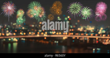 Fuochi d'artificio colorati su sfocato bokeh città di notte le luci sullo sfondo Foto Stock