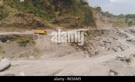 Autocarro pesante carico di montagna su strada sterrata verso la gola. vista aerea canyon off-road carrello di costruzione Foto Stock
