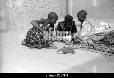 La Nigeria Africa 3 giovani ragazzi condividendo cibo insieme degli anni cinquanta Foto Stock