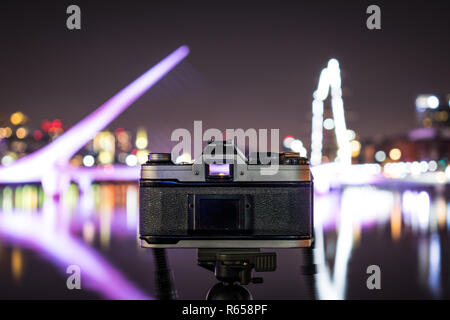 Film Vintage fotografia fotocamera rivolta verso il moderno, luminoso paesaggio urbano di notte. A Puerto Madero Buenos Aires Foto Stock