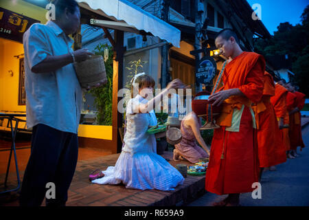 Tak Bat rituale - I monaci buddisti ricevere riso e cibo da pupulation in mattina presto a Luang Prabang, Laos, Asia Foto Stock