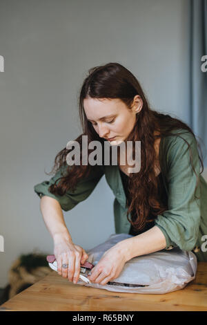 Foto di giovani caucasici che fiorista è di avvolgere accuratamente una corona di Avvento per un client nel proprio negozio di fiori Foto Stock