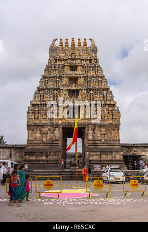 Belur, Karnataka, India - 2 Novembre 2013: pietra marrone Gopuram di ingresso principale visto dalla strada bianca contro il cielo nuvoloso. Il Karnataka Rajyotsava segno Foto Stock