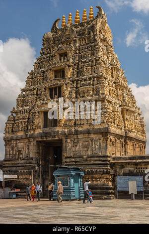 Belur, Karnataka, India - 2 Novembre 2013: pietra marrone Gopuram di ingresso principale visto da dentro il tempio contro il cielo blu. Cabine, segni e persone. Foto Stock