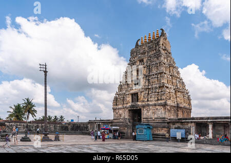 Belur, Karnataka, India - 2 Novembre 2013: pietra marrone Gopuram di ingresso principale visto da dentro il tempio contro il cielo blu. Cabine, segni e persone. C Foto Stock