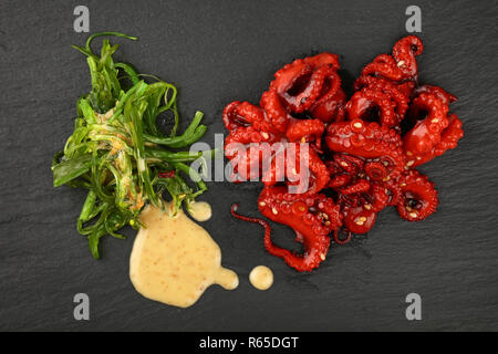 Frutti di mare polipetti e insalata di alghe marine su nero Foto Stock