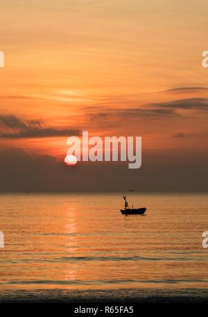 Un fiery orange sunrise sky che si affaccia sul mare della cina del sud a Vung Lam Bay Vietnam. Con un barche da pesca in silhouette. Foto Stock