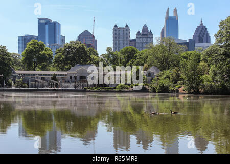 Famiglia Swan il nuoto nel lago del parco piemontese di Atlanta e incredibile paesaggio urbano e riflessi nell'acqua Foto Stock