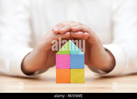 In legno colorato casa blocco protetto da mani Foto Stock