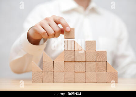 Mano d'uomo di impilamento dei blocchi di legno. Business development concept Foto Stock