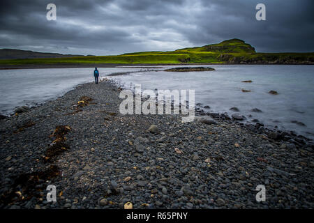 Persona solitaria su terreni sassosi Sandbank a bassa marea sull'Isola di Skye in Scozia Foto Stock